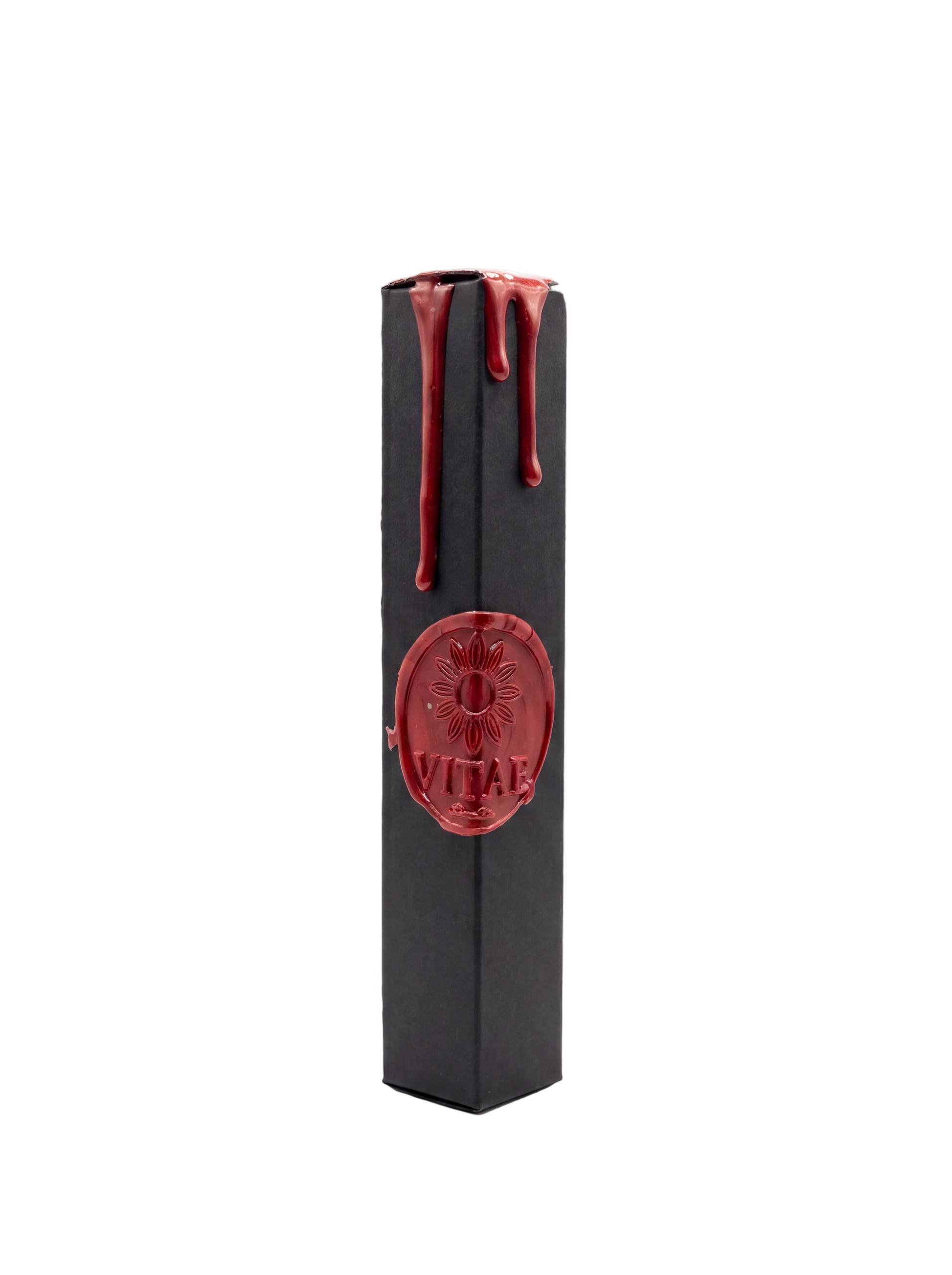 A tall, narrow black rectangular box with glossy red wax drips along the top and a red embossed oval seal in the center featuring a flower and the word 'VITAE'.